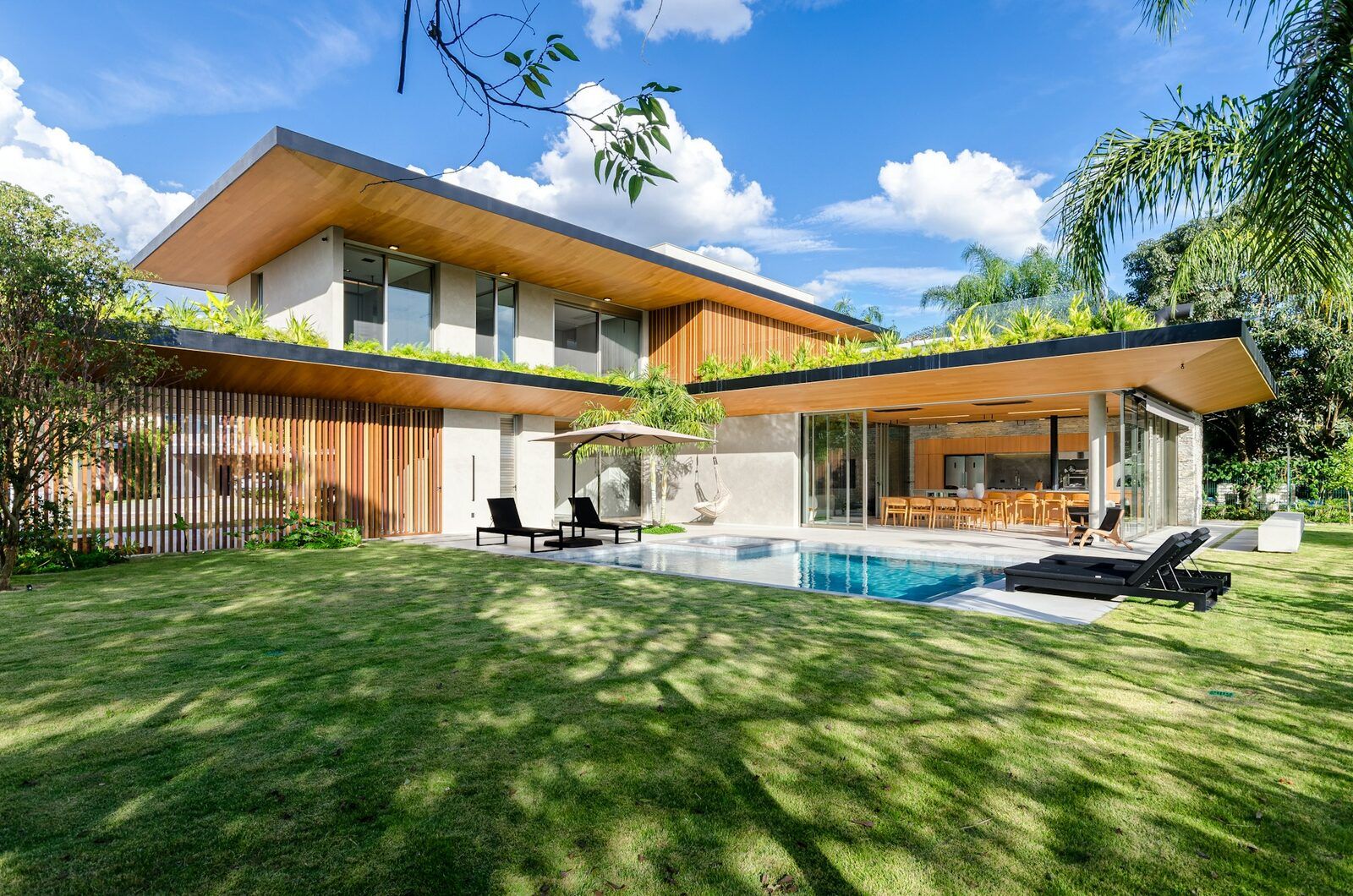 Ein modernes Tropenhaus mit Pool und weitem Rasen